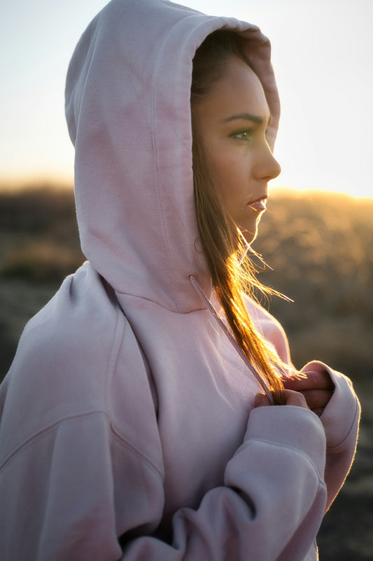 a woman in a pink hoodie standing in a field