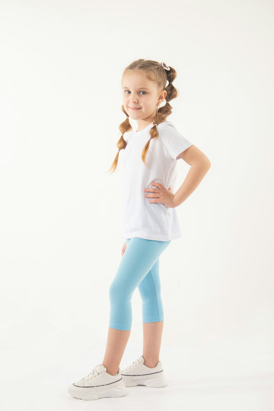 a little girl in a white shirt and blue leggings