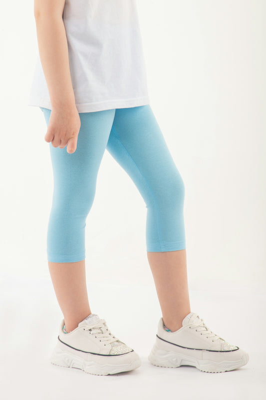 a little girl in a white shirt and blue leggings