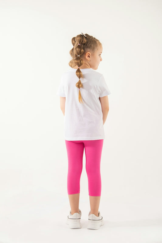 a little girl in a white shirt and pink leggings