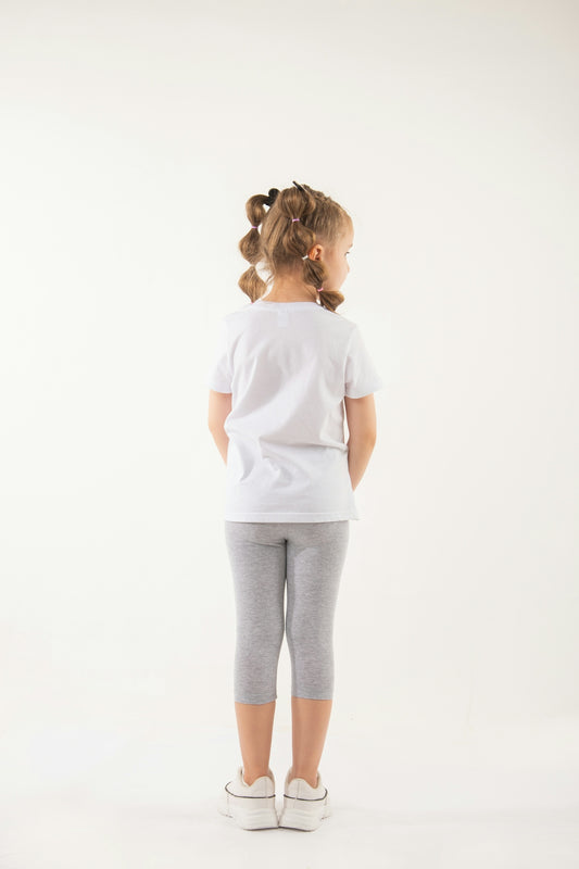 a little girl standing in front of a white background