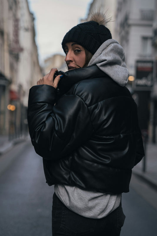 a woman in a black jacket is standing on the street