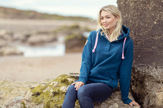 A woman in a blue hoodie sitting on a rock