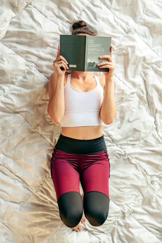 A woman laying on a bed reading a book