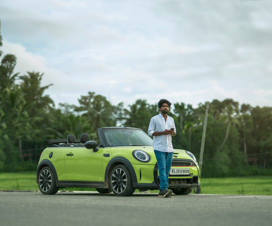 A man standing next to a green mini cooper