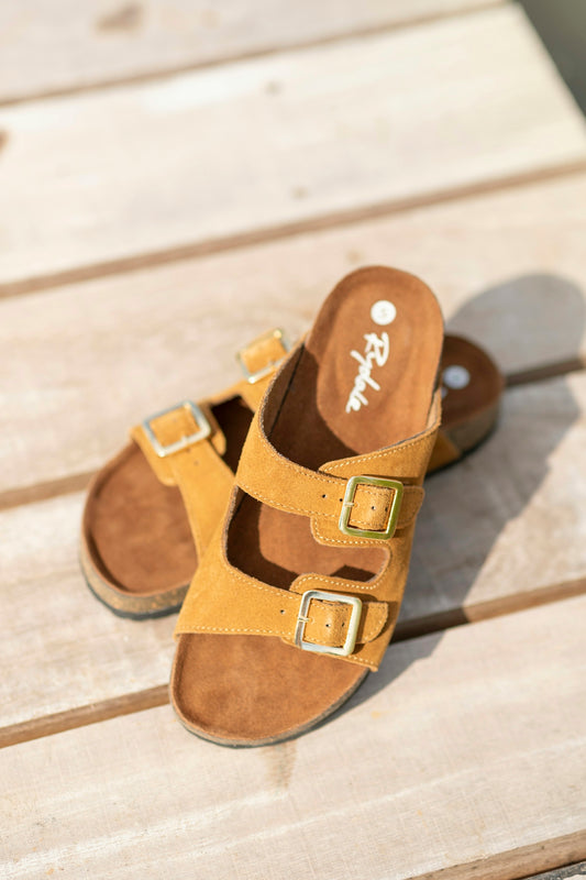 A pair of brown sandals sitting on top of a wooden floor