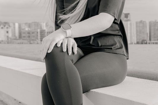 Woman in athletic wear sitting outdoors with city skyline.