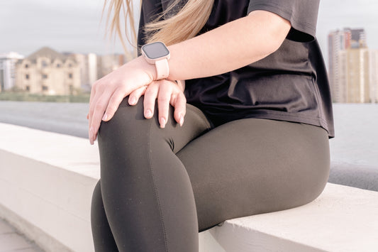 Woman wearing fitness tracker sits outdoors